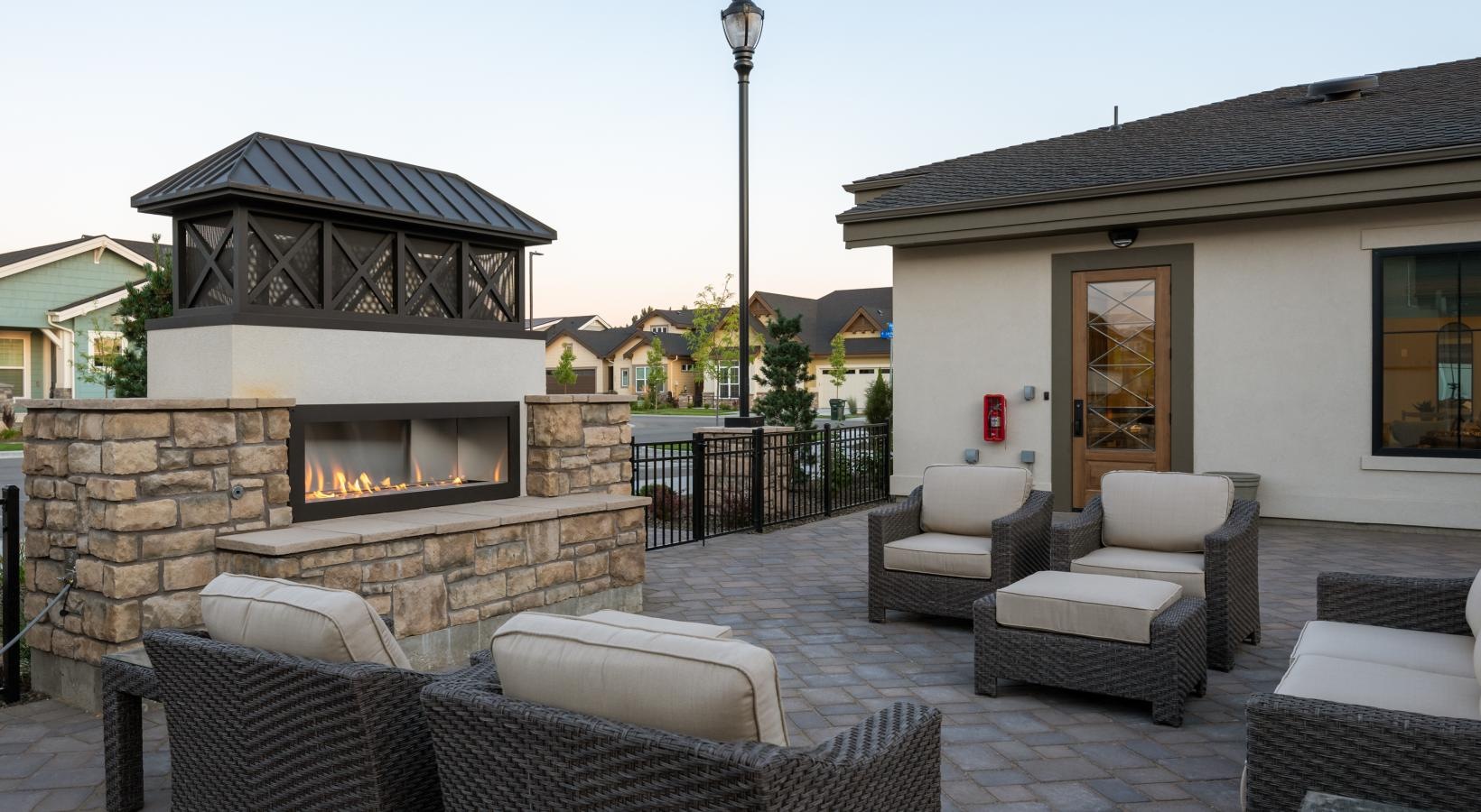 a patio with a fireplace and chairs